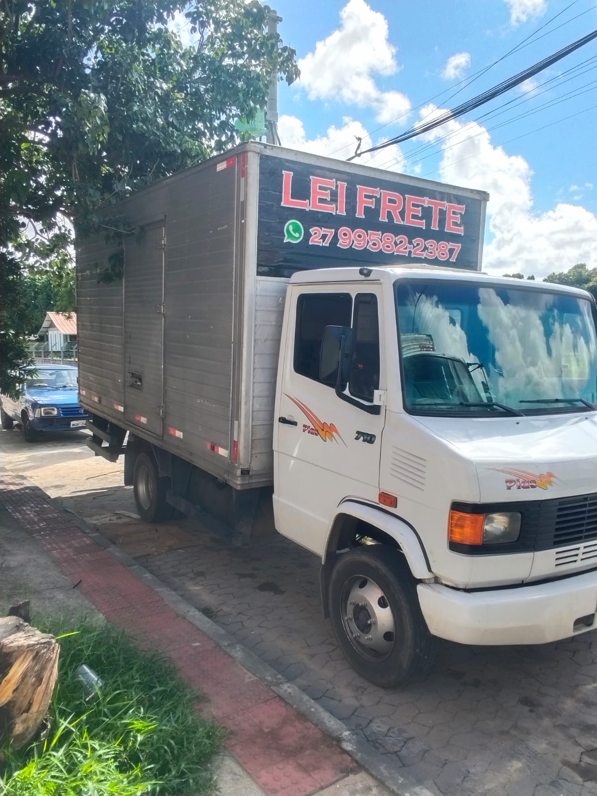 Mercedes 710 da Lei Frete estacionado na calçada, com o letreiro LEI FRETE e o número de WhatsApp no baú